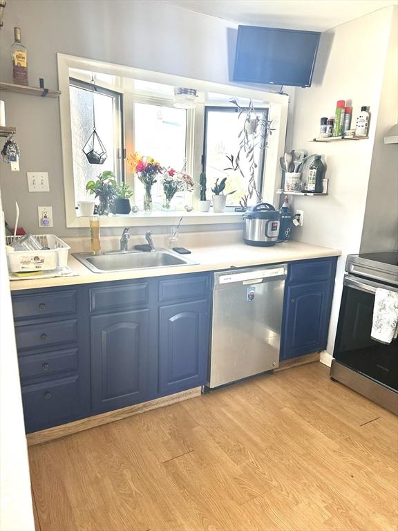 kitchen with blue cabinets, stainless steel appliances, a sink, and light countertops