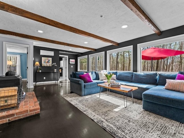 living area with wood finished floors, baseboards, a wall mounted AC, beam ceiling, and a textured ceiling