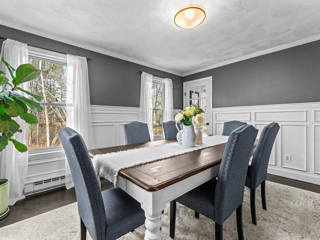 dining room featuring baseboard heating, plenty of natural light, a textured ceiling, and wood finished floors