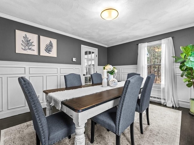 dining area featuring a textured ceiling, wood finished floors, and crown molding