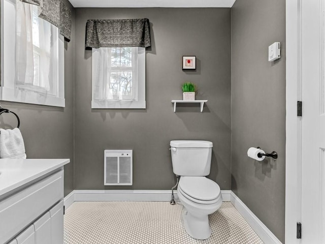 half bathroom featuring vanity, baseboards, visible vents, tile patterned flooring, and toilet