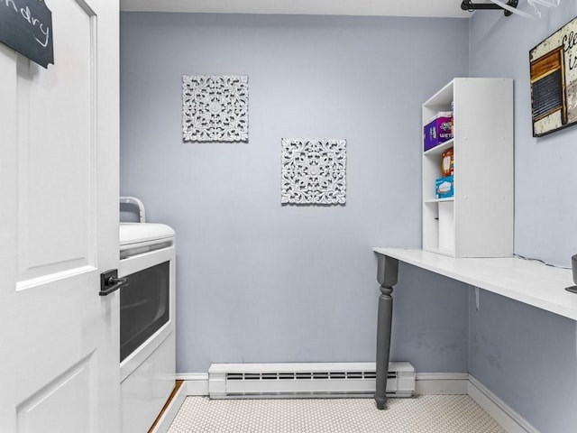 clothes washing area featuring laundry area, baseboards, baseboard heating, and washer and clothes dryer