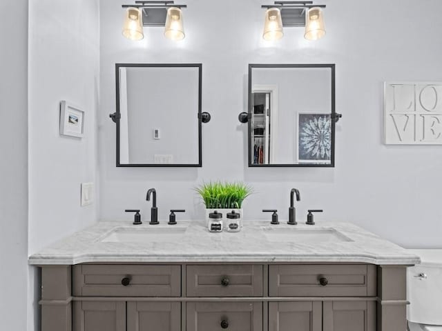 bathroom with double vanity, toilet, and a sink