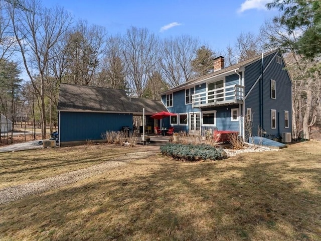 rear view of house with a deck, central AC unit, a chimney, and a yard