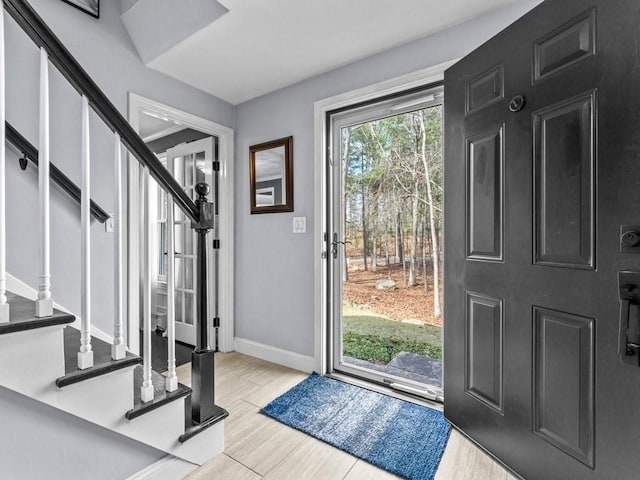 entrance foyer with baseboards, wood finished floors, and stairs