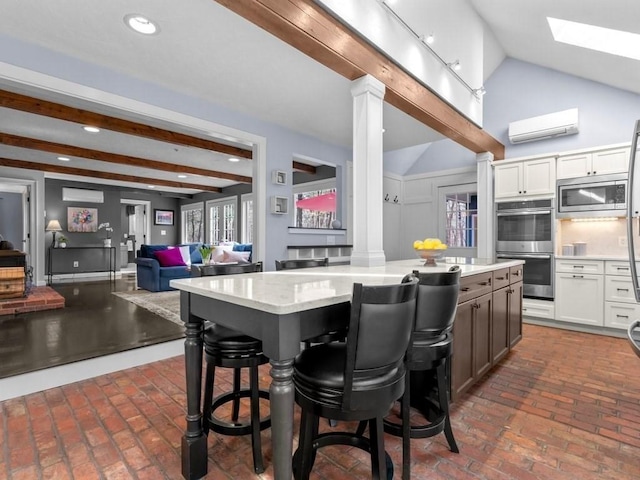 kitchen with a wall mounted AC, a breakfast bar, a skylight, appliances with stainless steel finishes, and a center island