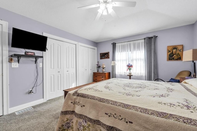 bedroom with ceiling fan, visible vents, baseboards, carpet, and two closets