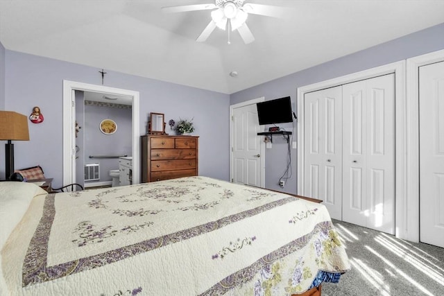 bedroom with two closets, visible vents, carpet flooring, ceiling fan, and vaulted ceiling