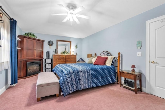 carpeted bedroom with a glass covered fireplace, a ceiling fan, and baseboards