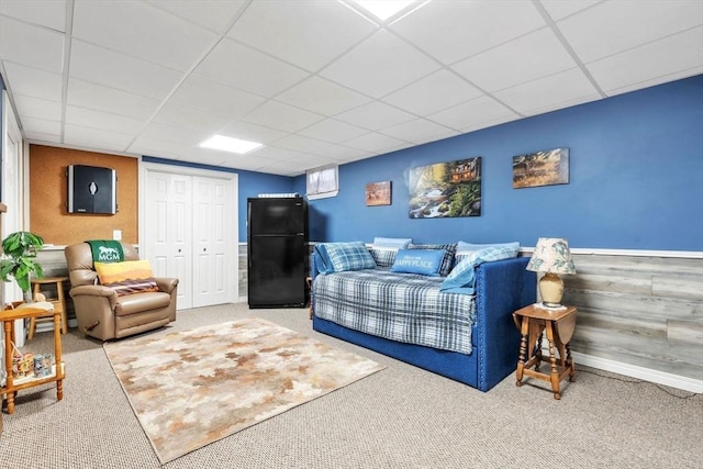 living area featuring a paneled ceiling and carpet