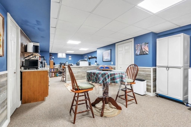 dining space with a paneled ceiling and light colored carpet