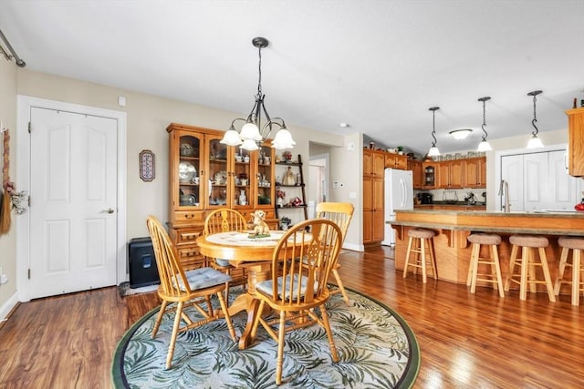 dining room with a chandelier, dark wood finished floors, and baseboards