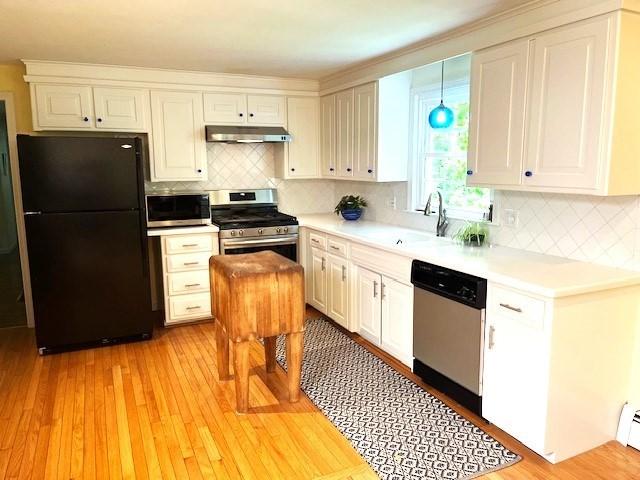 26 N Hill Rd, Westford, MA 01886 - kitchen with appliances with stainless steel finishes, under cabinet range hood, a sink, light countertops, and tasteful backsplash