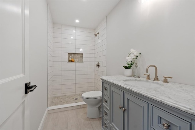 bathroom featuring vanity, tiled shower, and toilet