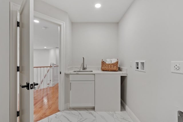 clothes washing area with hookup for a washing machine, sink, and cabinets