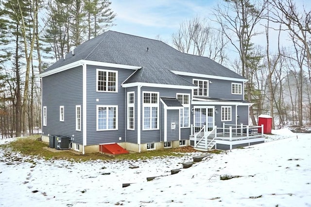 snow covered property with a wooden deck and central air condition unit