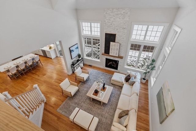 living room featuring a towering ceiling, a fireplace, and hardwood / wood-style floors