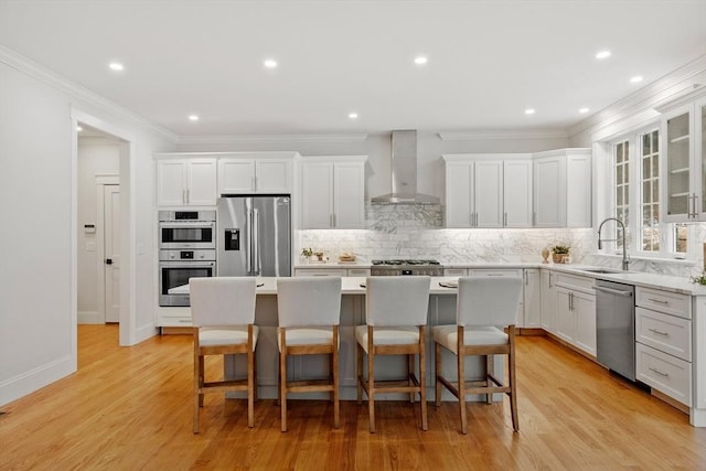 kitchen featuring a kitchen island, appliances with stainless steel finishes, a kitchen bar, and wall chimney exhaust hood