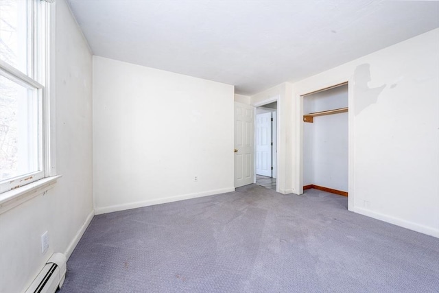 unfurnished bedroom featuring a baseboard heating unit, carpet, a closet, and baseboards