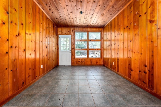 spare room with dark tile patterned flooring, wood ceiling, and wood walls