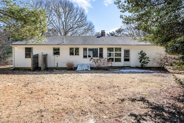 back of property with roof with shingles and a chimney