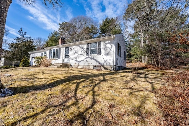 view of front of home featuring entry steps, a chimney, and a front yard