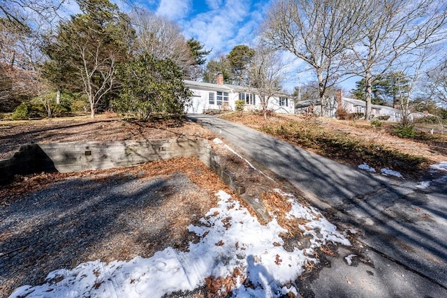 view of front facade featuring driveway and a chimney