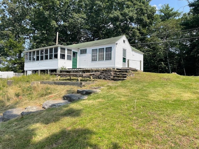 view of front facade with a front yard and a sunroom