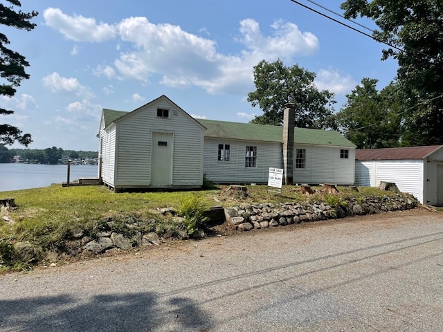 view of front of property featuring a water view and a storage shed