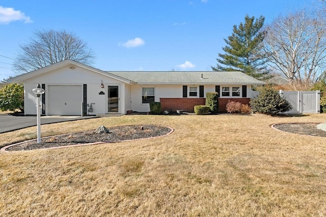 single story home featuring an attached garage, brick siding, driveway, a gate, and a front yard