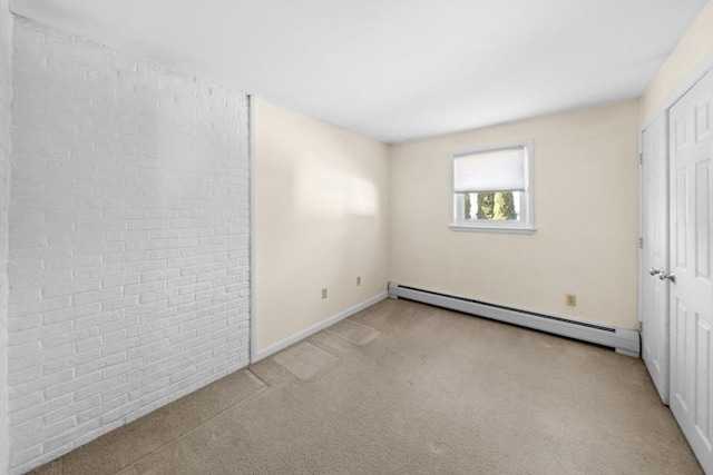 unfurnished bedroom with carpet, brick wall, ensuite bath, and baseboard heating