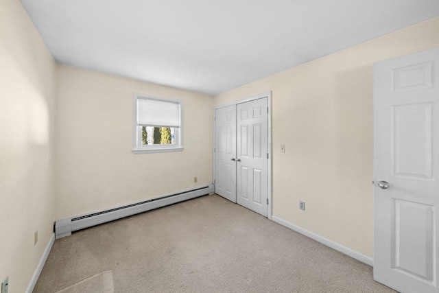 unfurnished bedroom with carpet, baseboards, baseboard heating, and a closet