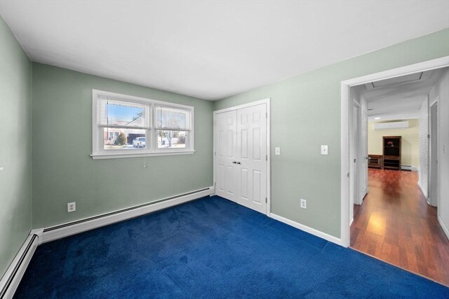 unfurnished bedroom featuring a baseboard heating unit, a closet, baseboards, and a wall mounted AC