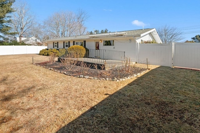 ranch-style house featuring a deck, a front yard, and a fenced backyard