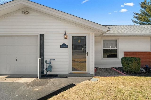 doorway to property with a garage and roof with shingles