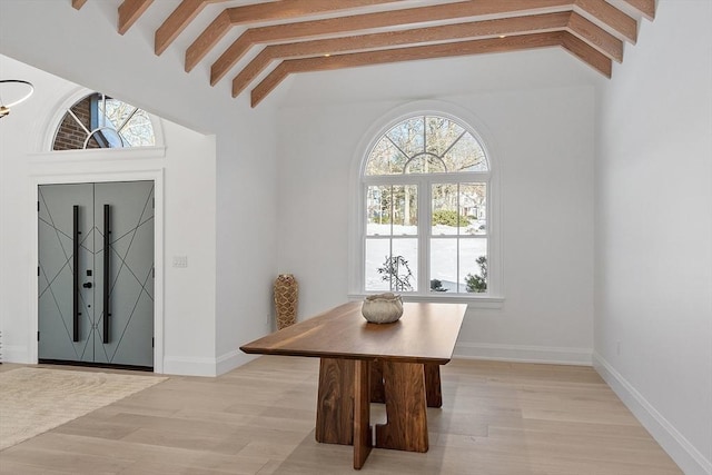 dining space with lofted ceiling with beams, baseboards, and light wood-style floors