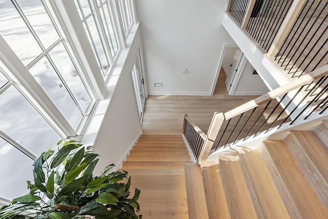 staircase featuring a high ceiling, wood finished floors, and baseboards