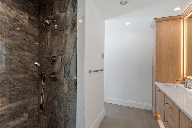 bathroom featuring recessed lighting, baseboards, vanity, and a marble finish shower