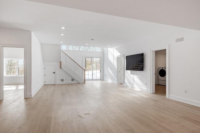 unfurnished living room with visible vents, stairs, washer / clothes dryer, and light wood-style flooring