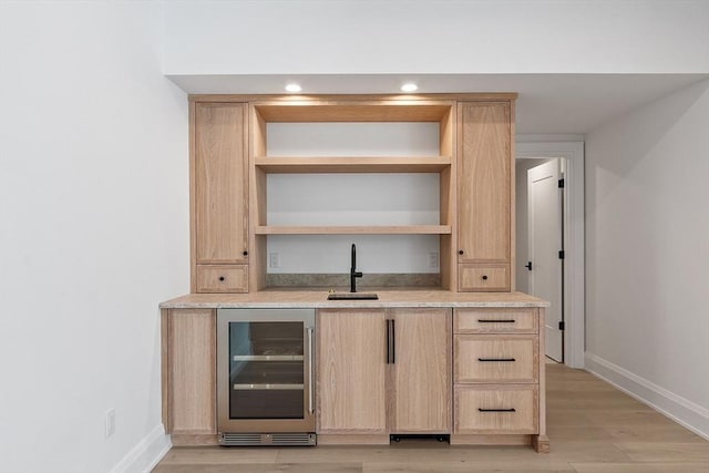 bar with light wood finished floors, wine cooler, baseboards, and a sink