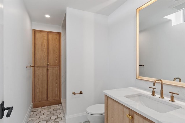 bathroom featuring toilet, recessed lighting, baseboards, and vanity