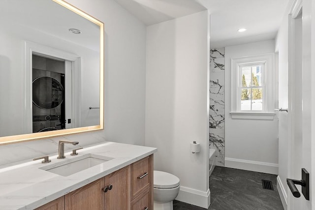 full bath featuring toilet, stacked washer / dryer, visible vents, marble finish floor, and washtub / shower combination