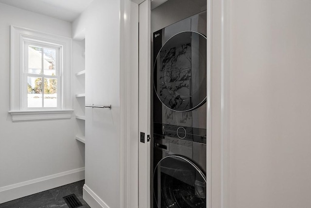 interior space featuring stacked washer / drying machine, visible vents, and baseboards