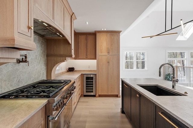 kitchen with range with two ovens, wine cooler, decorative light fixtures, light countertops, and a sink