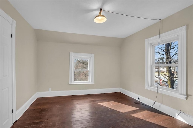 empty room featuring dark hardwood / wood-style flooring, lofted ceiling, and a wealth of natural light