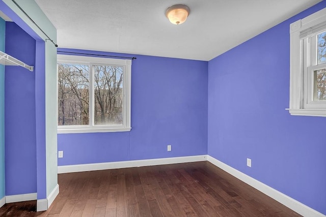 unfurnished bedroom with dark hardwood / wood-style flooring and multiple windows