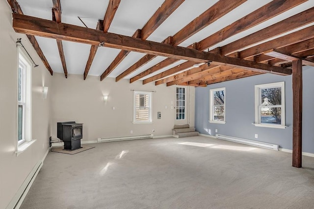 unfurnished living room featuring beam ceiling, a wood stove, and a baseboard heating unit