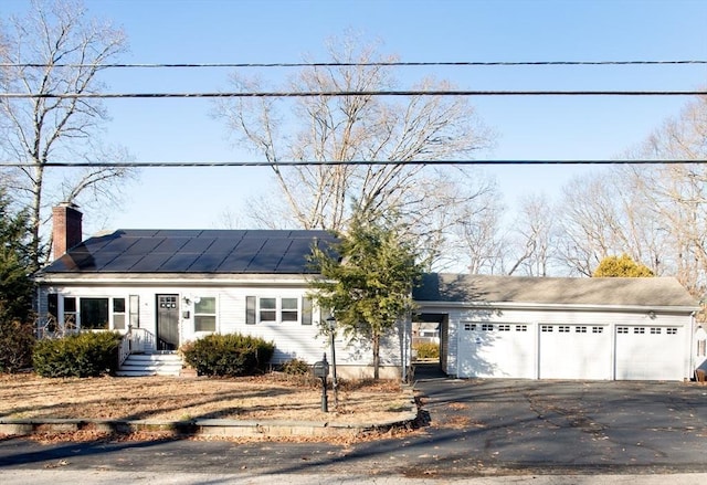 single story home with solar panels and a garage