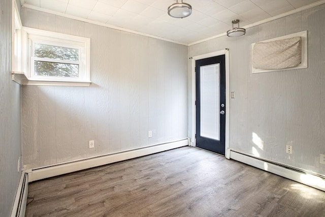 spare room featuring baseboard heating, crown molding, and hardwood / wood-style floors