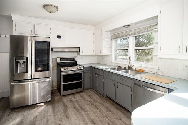 kitchen featuring gray cabinetry, white cabinets, ventilation hood, sink, and appliances with stainless steel finishes